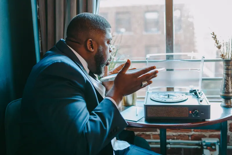 A resident in a navy suit telling a story beside the record player by the window