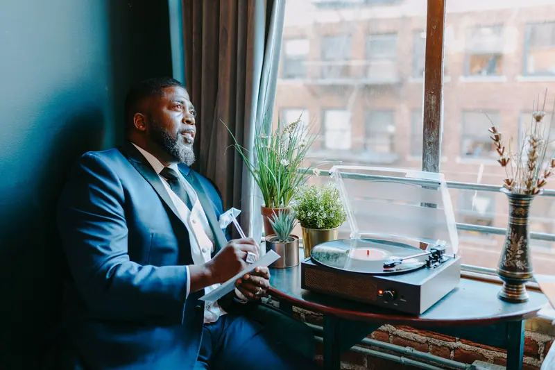 A resident in his good suit resting by the window next to the record player
