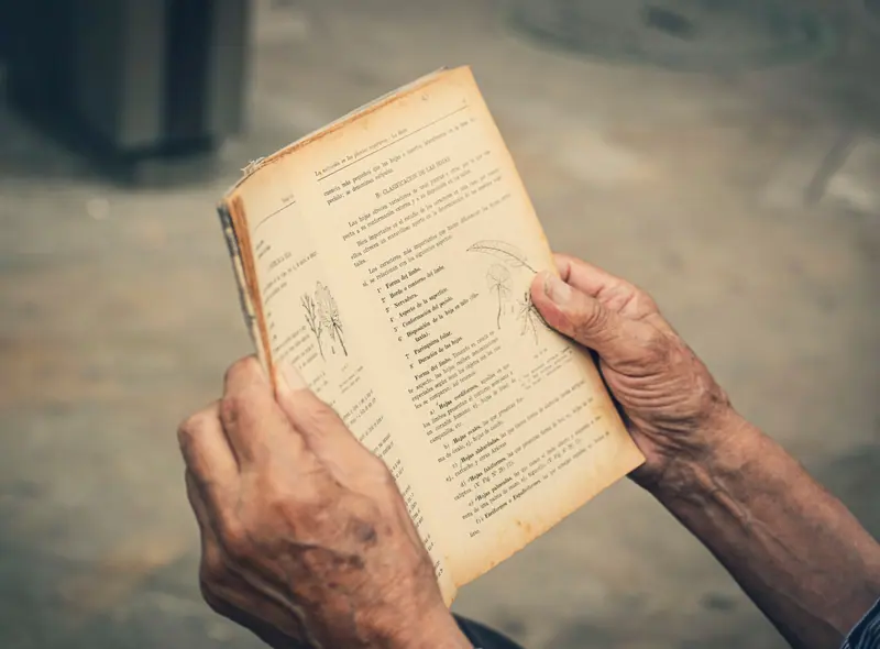 A resident's hands holding an old hymnal