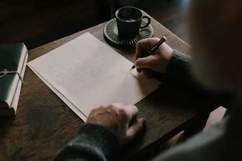 A resident writing a letter by hand at the desk with a cup of coffee