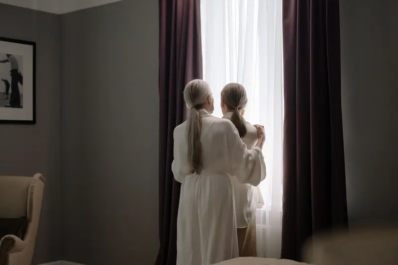 Two residents looking out the tall window together