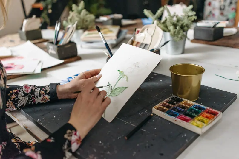 A watercolor of a flower stem taking shape at the studio table