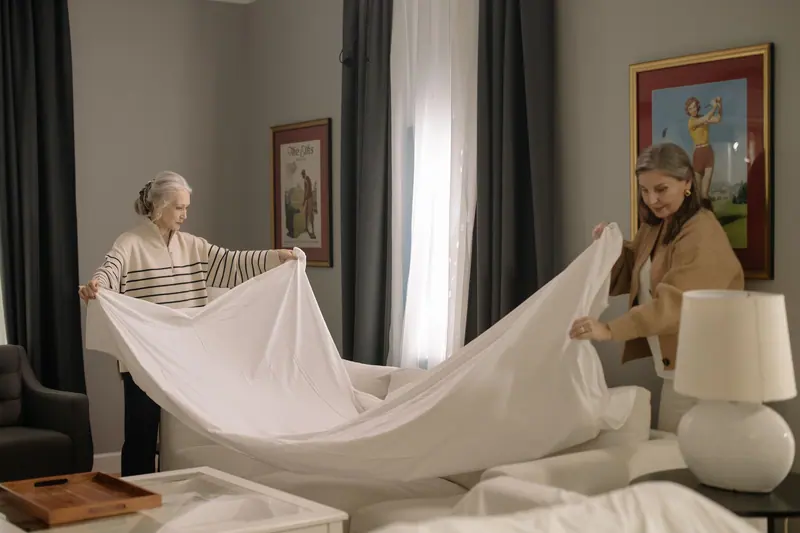 A resident and a caregiver making a bed together