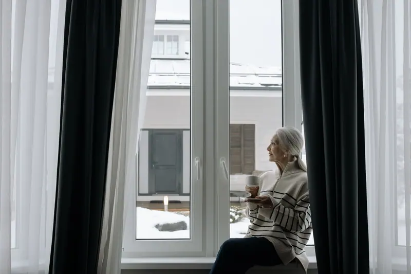 A resident with her tea by the tall window on a winter morning