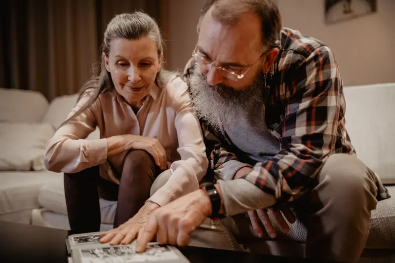 A couple turning pages on the sofa