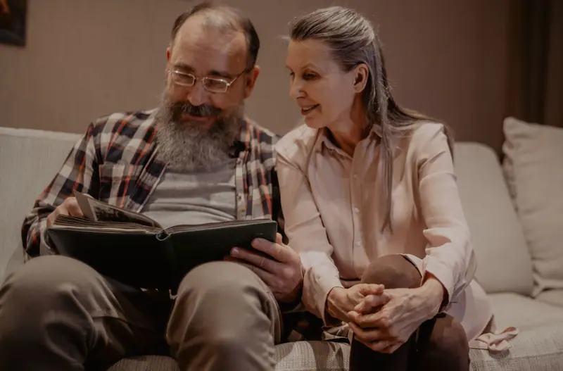 A resident and his wife paging through an album on the couch