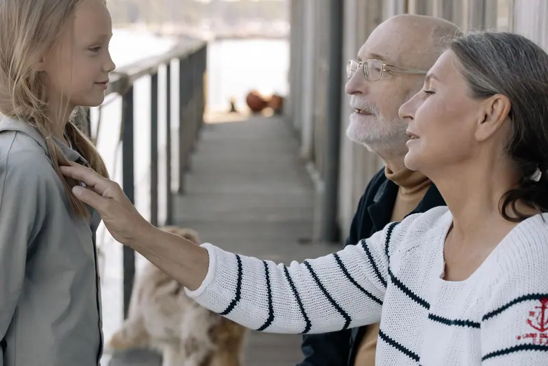 A grandmother tucking her granddaughter's hair behind her ear on the dock