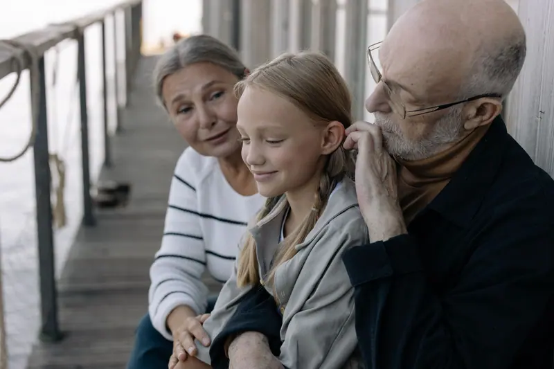 Grandparents and granddaughter sitting together on the boardwalk
