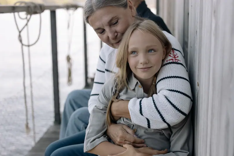 A grandmother hugging her granddaughter on the dock