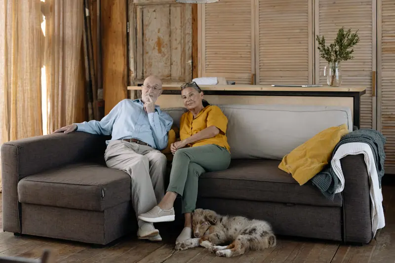 A resident and his wife relaxing on the sofa with the house cat