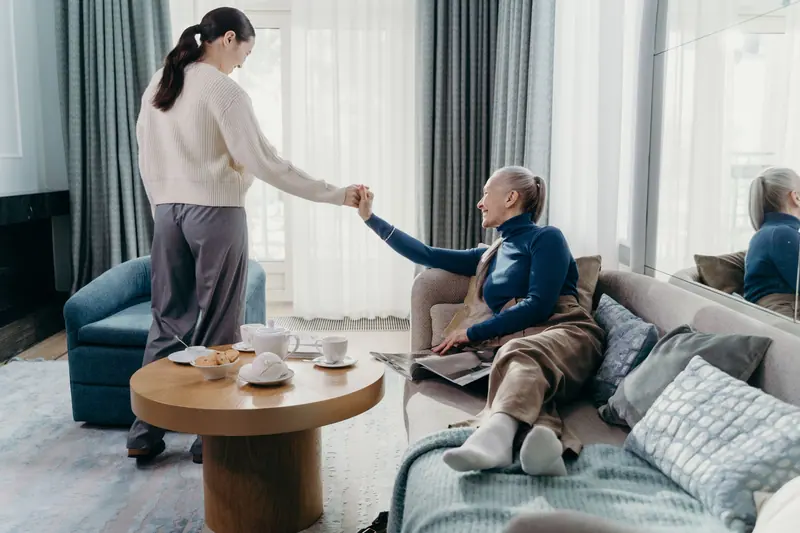 A caregiver helping a resident up from the sofa