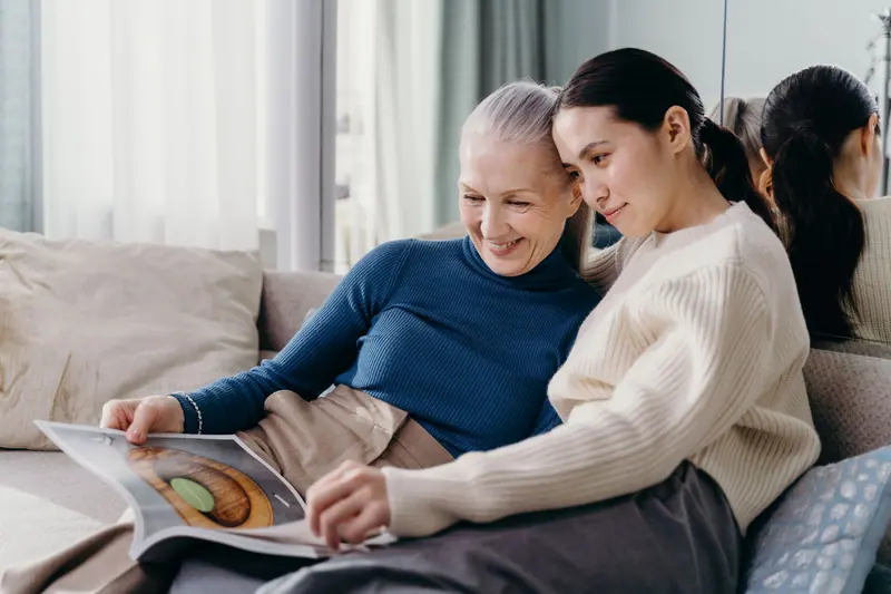 A resident and her daughter looking at a magazine on the sofa