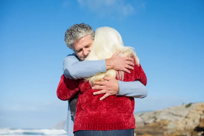 A couple in a long hug under a blue sky