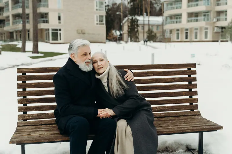 A couple bundled up together on a winter bench