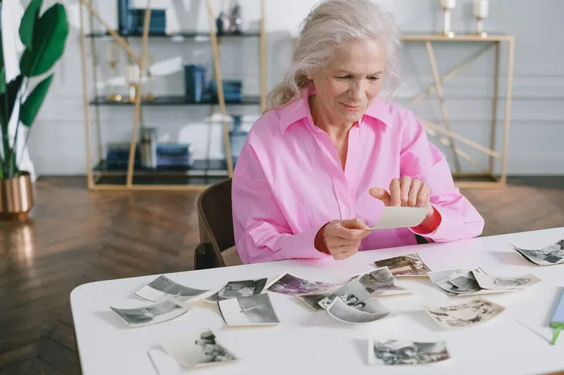 A resident in a pink blouse arranging old photographs for a collage