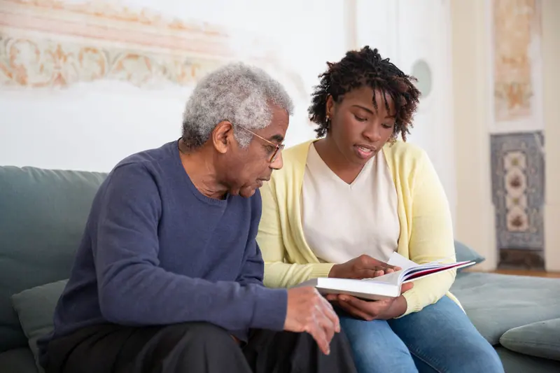 A caregiver and a resident talking over a book