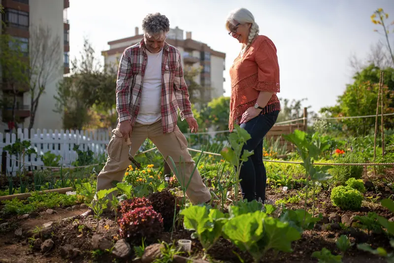 A resident and his wife working the garden rows together