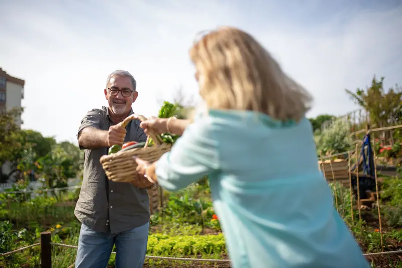 A resident handing a basket of greens to a visiting daughter