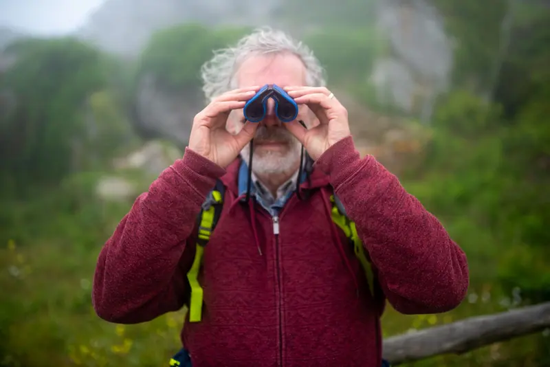 A resident in a red fleece watching birds through binoculars