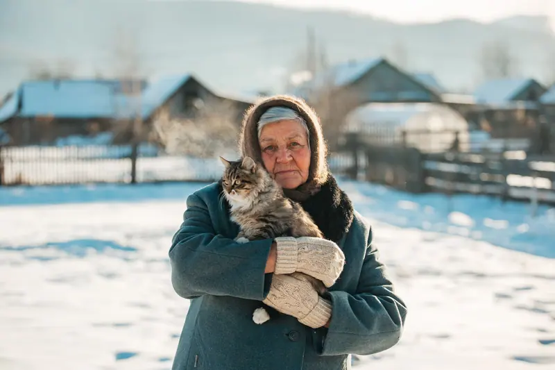 A resident in a winter coat cuddling a long-haired cat