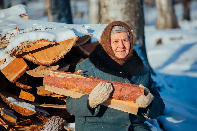 A resident carrying firewood in the snow, smiling