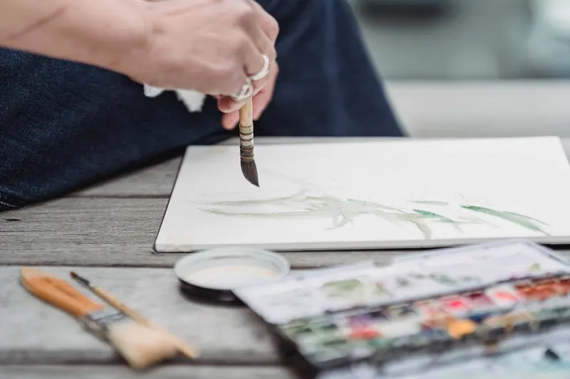 A resident painting a fern study at the porch table
