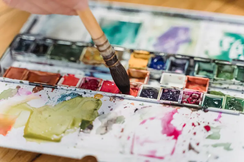 A watercolor palette in use, colors bleeding together