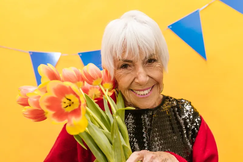 A resident with a bouquet of orange tulips at the spring party