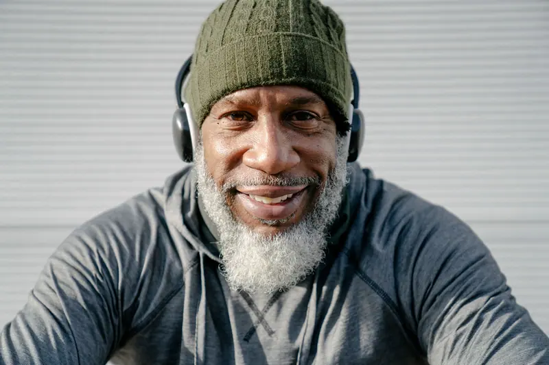 A smiling resident in a green knit cap and headphones