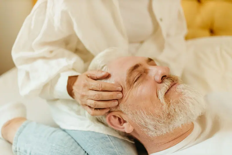A resident with his eyes closed during a gentle head massage