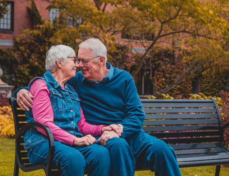 An older couple sharing a laugh on a park bench