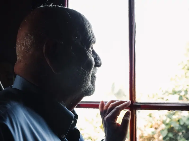 A resident with his hand on the window frame