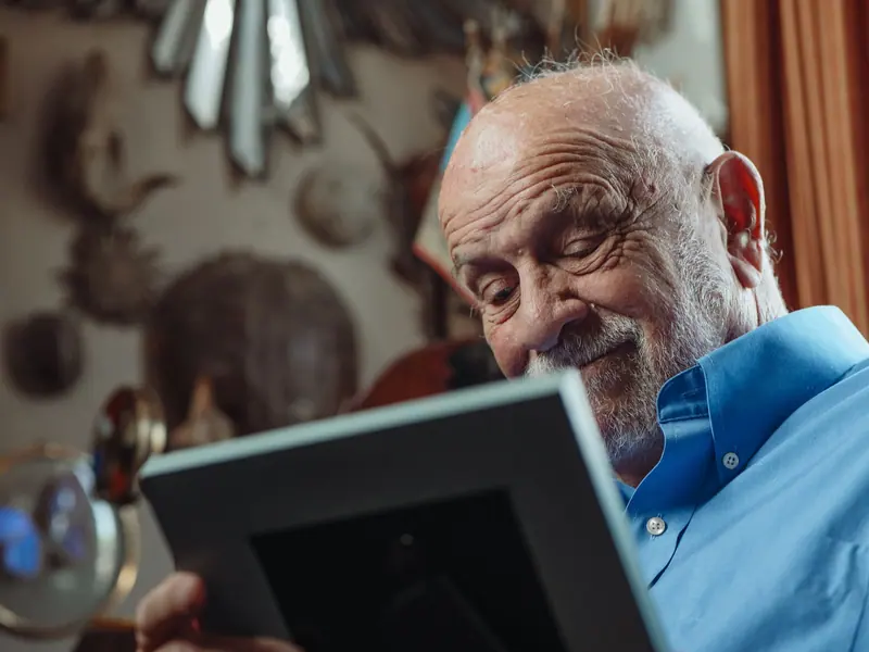 A resident smiling at a framed photo of his late wife
