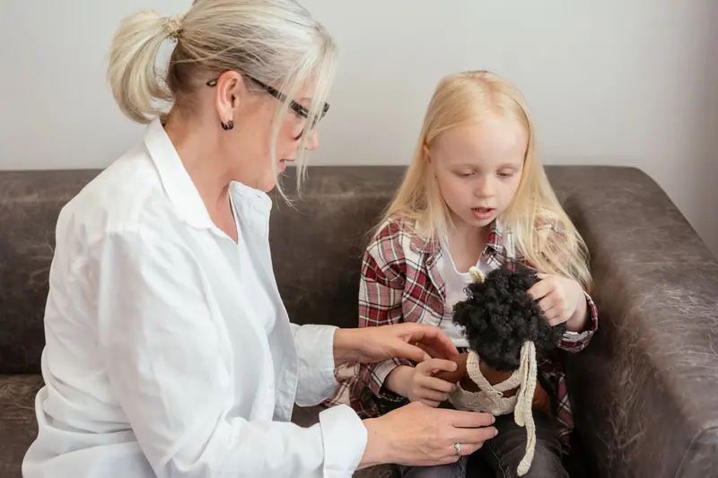 A caregiver helping a girl with a doll during free play