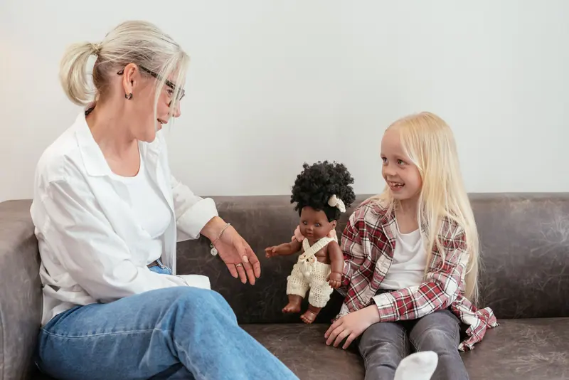 A caregiver and a preschooler laughing on the couch