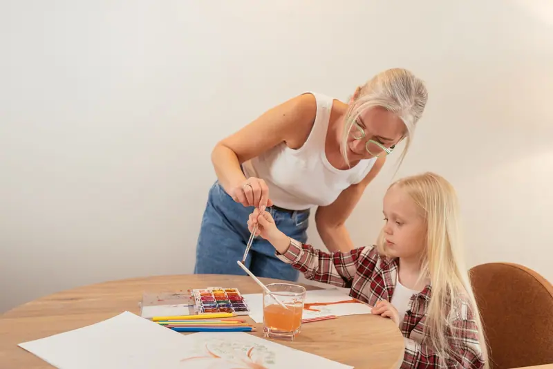 A caregiver painting watercolors with a preschooler