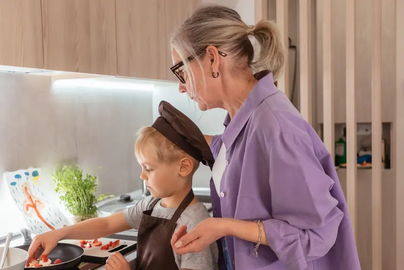A caregiver and a preschooler stirring cookie dough