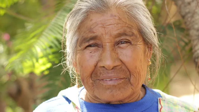 A resident with silver hair smiling in the garden