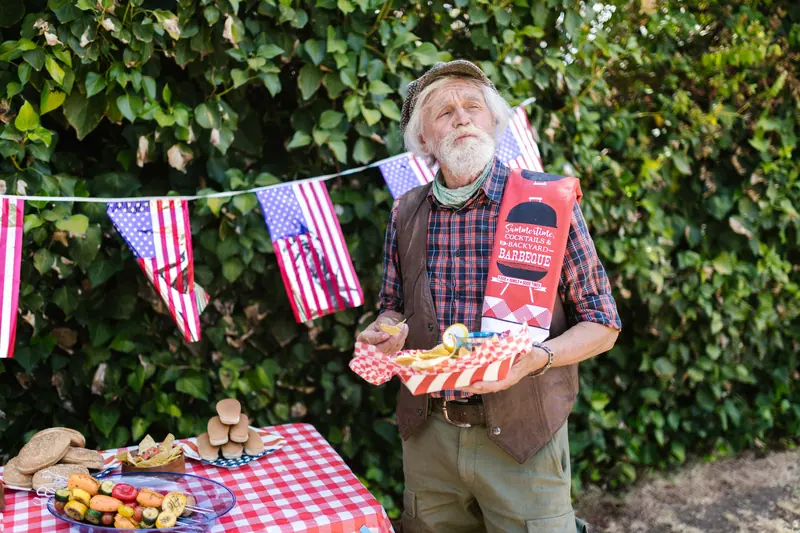 A resident carrying a plate of hot dogs past the bunting