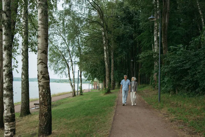 Two residents walking the path through the birches along the water