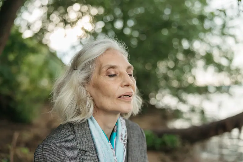 A resident with silver hair outside under the trees