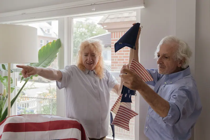 A resident and his wife hanging stars-and-stripes bunting for the Fourth