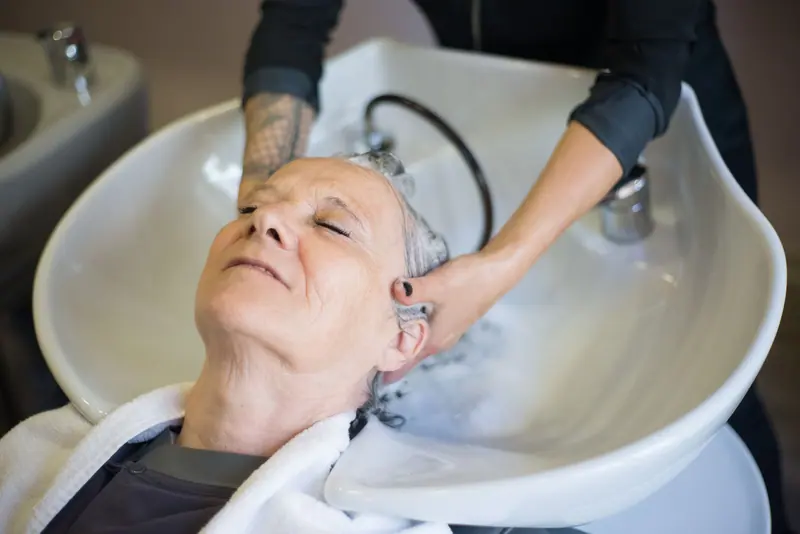 A resident with her eyes closed at the salon basin