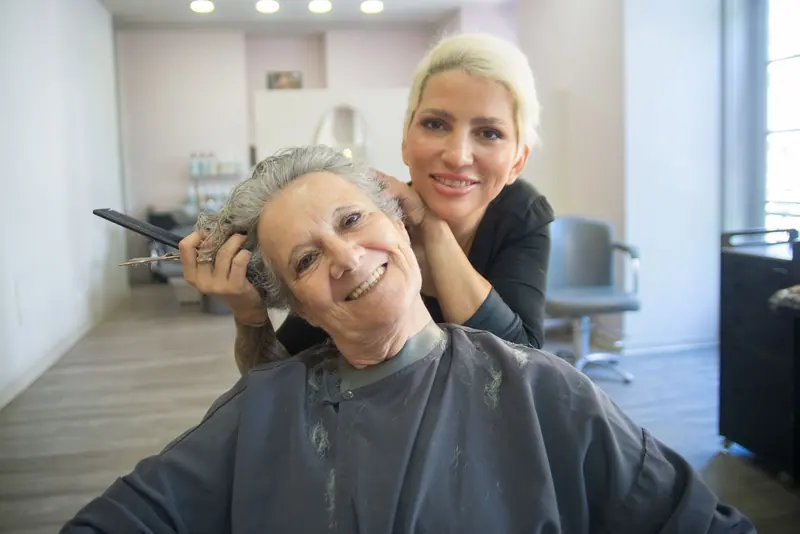 A resident smiling with the stylist in the beauty shop