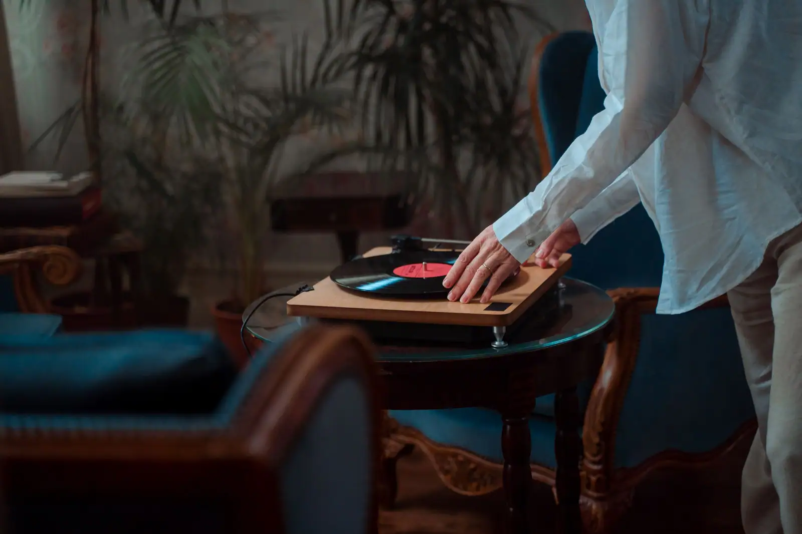 A person adjusting a vinyl record on a turntable in a cozy indoor setting.