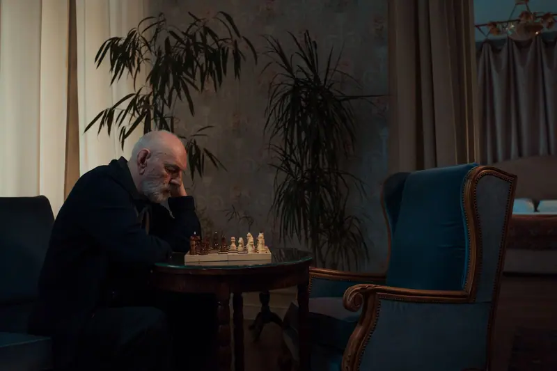 A resident studying a chessboard in the parlor