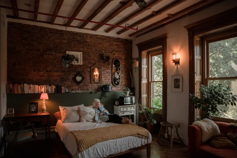 A resident resting in her room among plants and old furniture