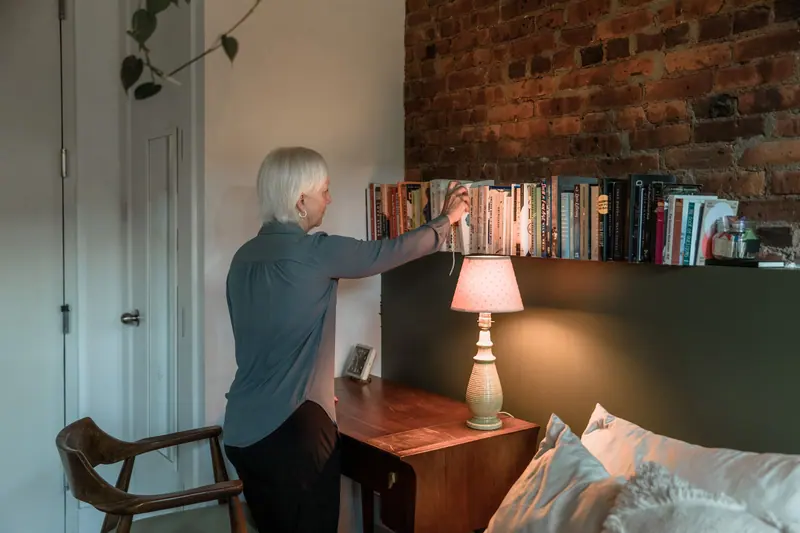A resident reaching for a book from the shelf above her desk