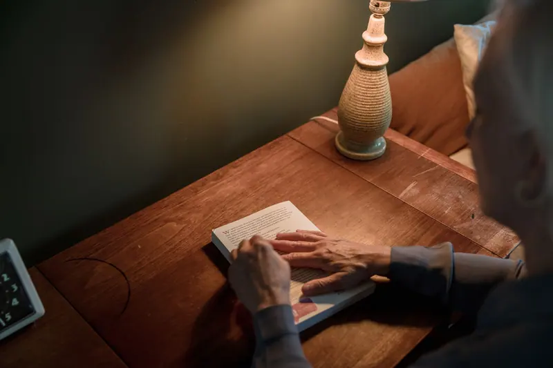 A resident's hands on a book in the lamplight