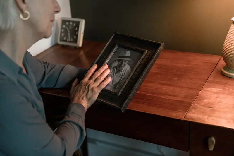 A resident holding a framed photograph at her bedside table